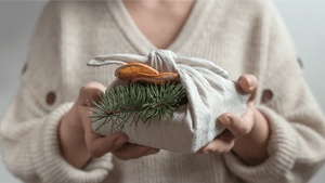 Christmas present wrapped in a fabric cloth decorated with dried orange and fir twig