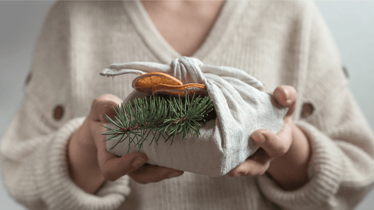 Christmas present wrapped in a fabric cloth decorated with dried orange and fir twig