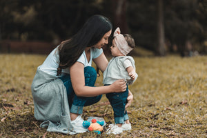 woman kneeling down and hugging a little girl in stylish outfit